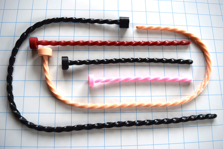 Spiral-twisted silicone urethral sounds shown in various lengths and colors on a blue grid background.