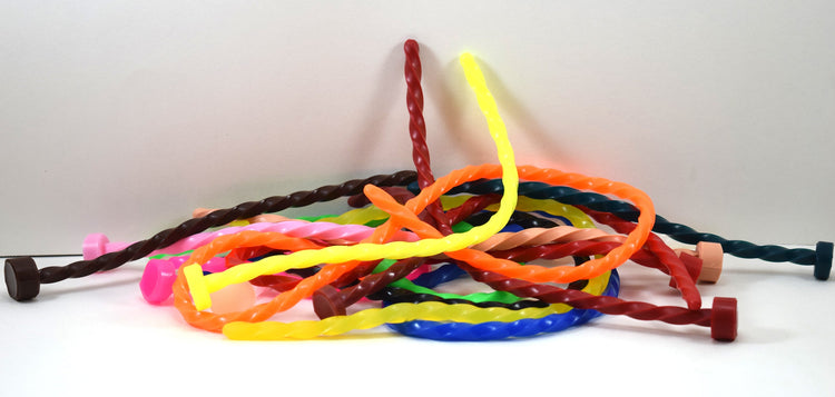 A large tangled heap of colorful spiral-twisted silicone urethral sounds against a plain white background.