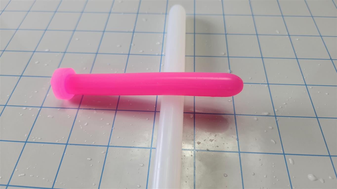 Bright pink SSND 14mm silicone sound called The Rod resting horizontally across a translucent white silicone rod on a blue grid mat.