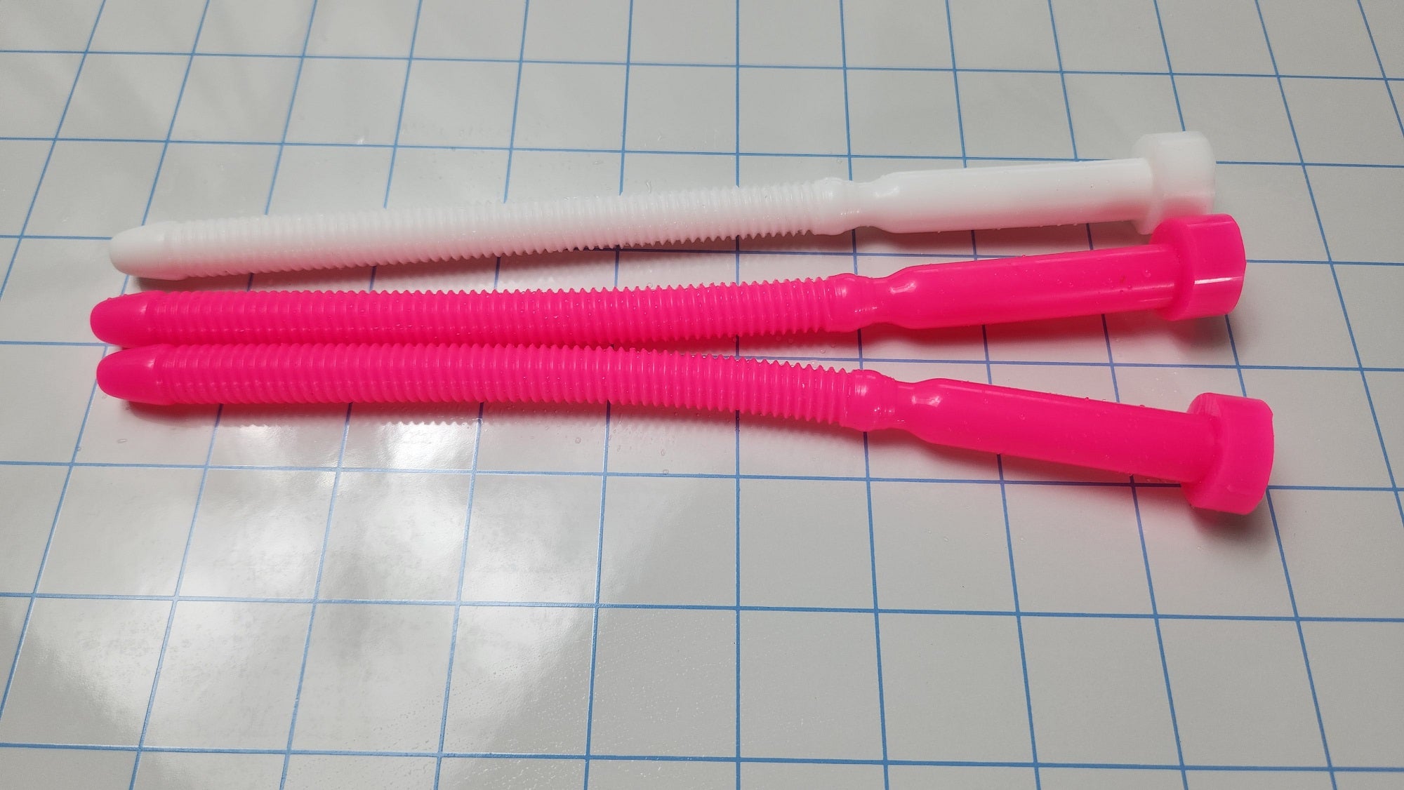 Three SSND-THREADED13 silicone urethral sounds (one white and two pink) displayed horizontally on a blue grid background, featuring an 8.3-inch insertable length and threaded texture.