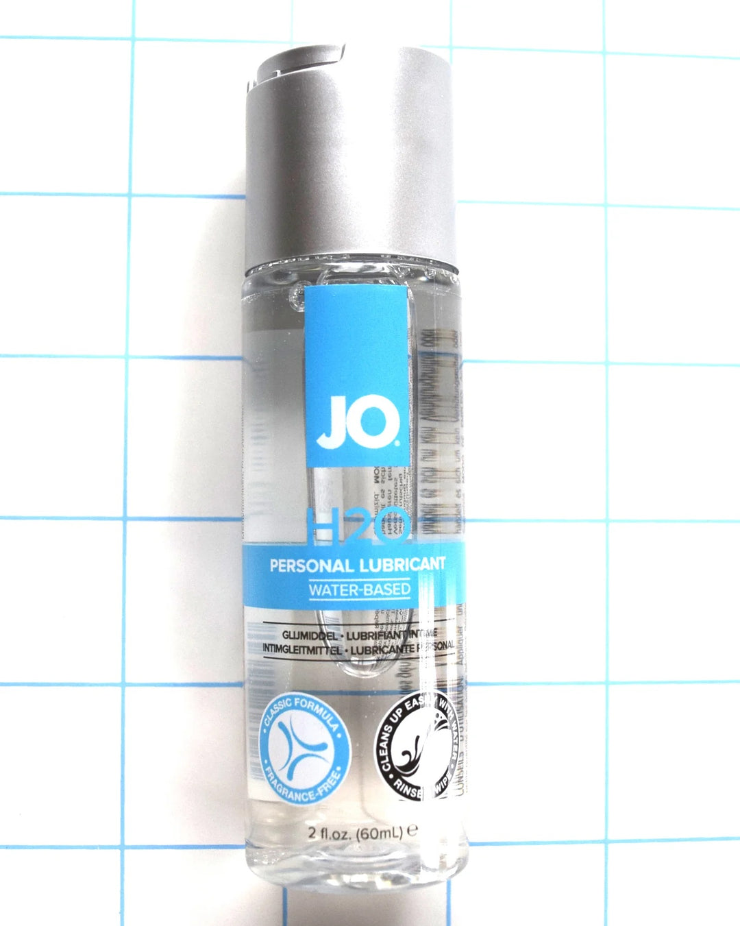 Front view of 2 oz System JO H2O water-based personal lubricant bottle on a blue grid background.