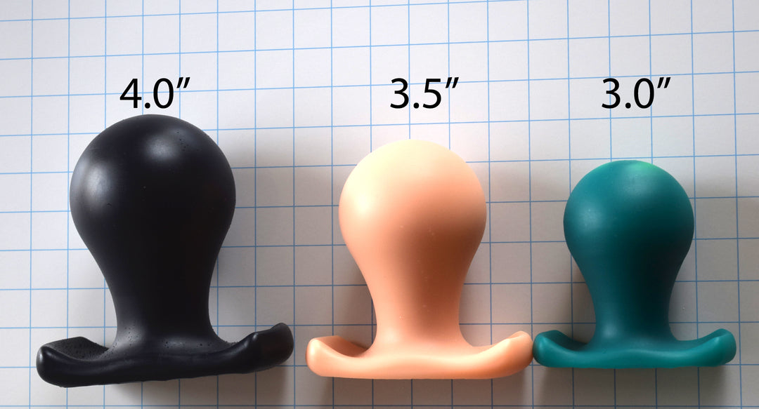 The Orb lineup displaying all three sizes (3.0", 3.5", and 4.0") of spherical silicone retention plugs in black, peach, and blue on a grid background.