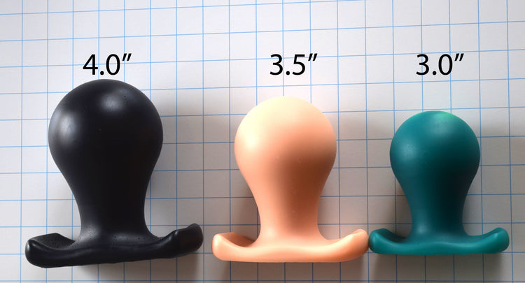 The Orb lineup displaying all three sizes (3.0", 3.5", and 4.0") of spherical silicone retention plugs in black, peach, and blue on a grid background.