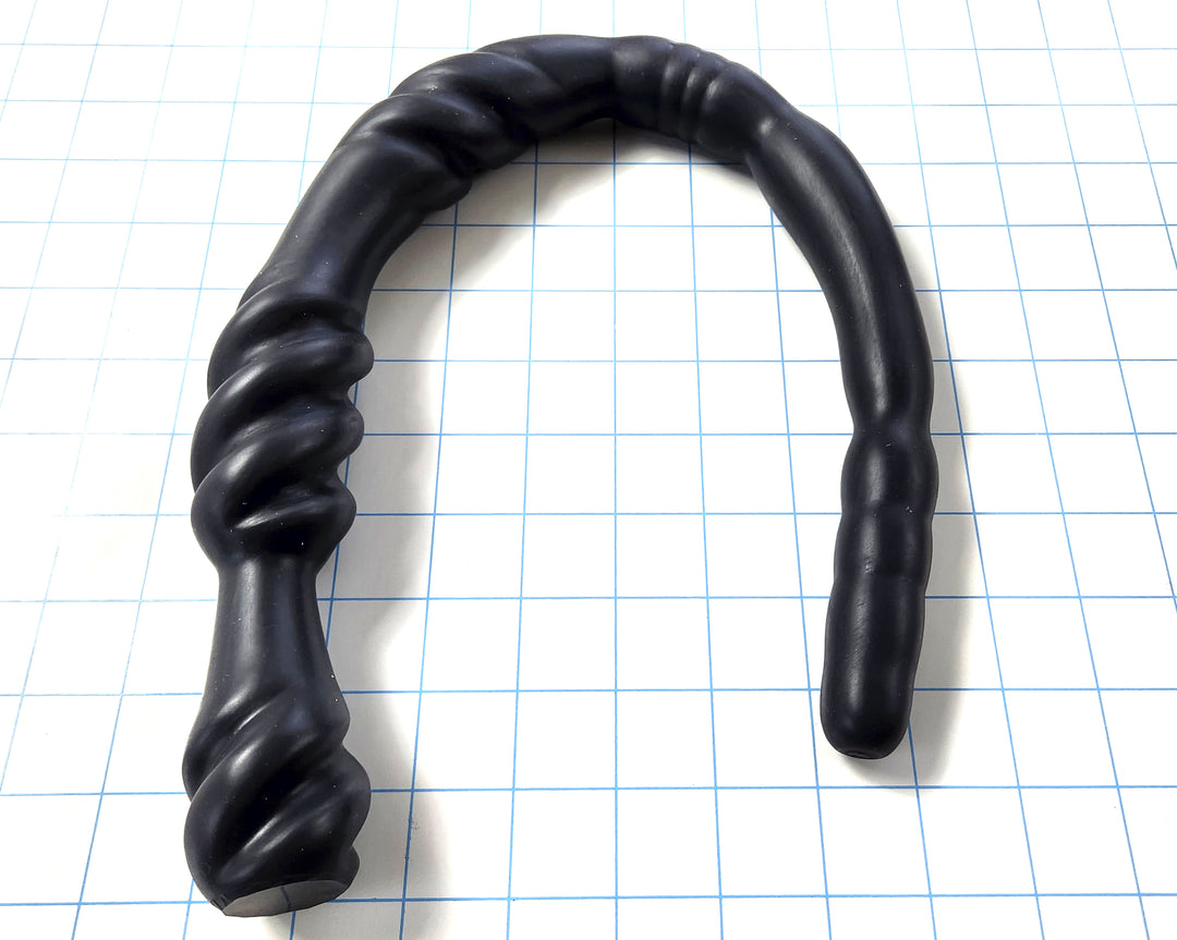 Black Triple Spiral 22-inch silicone nozzle featuring intricate spiraled textures and a graduated design for varied stimulation on a white grid background