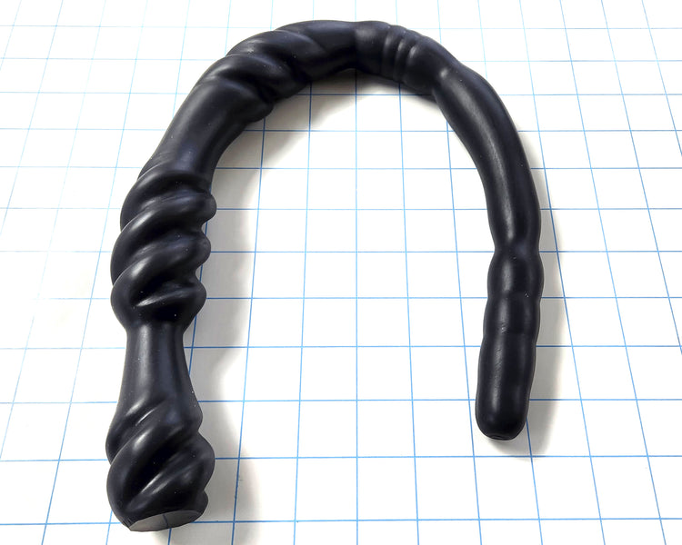 Black Triple Spiral 22-inch silicone nozzle featuring intricate spiraled textures and a graduated design for varied stimulation on a white grid background