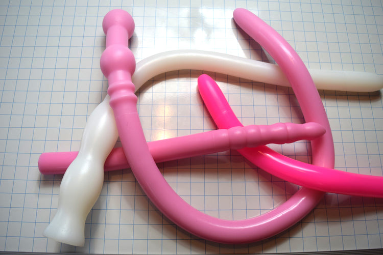 Assorted 1.6-inch diameter silicone colon tubes in various colors and designs, shown on a grid background