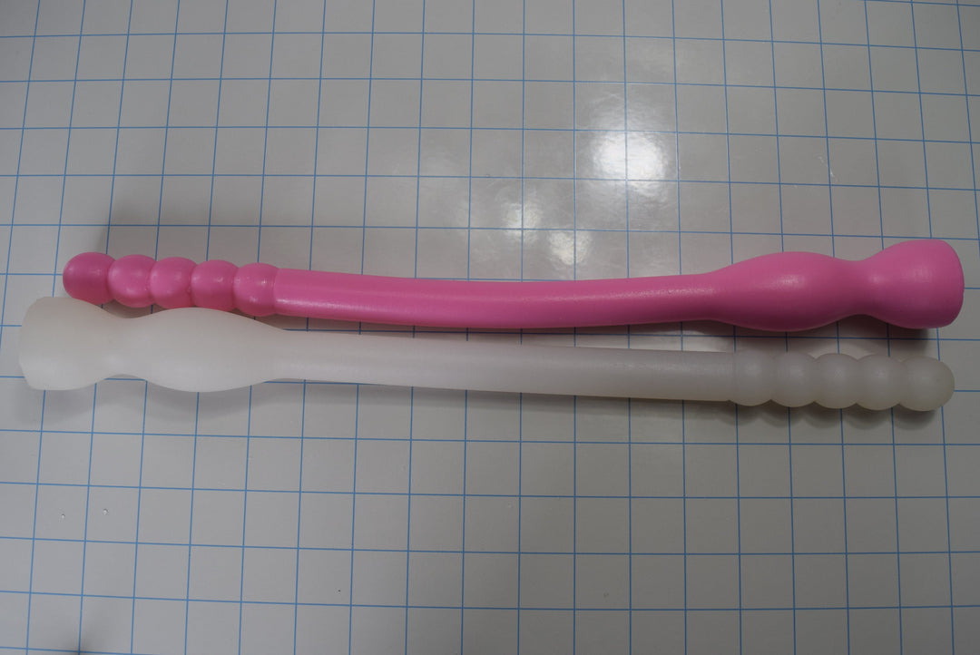 Side-by-side horizontal comparison of 12 inch and 16 inch Model F silicone colon nozzles in pink and translucent white.