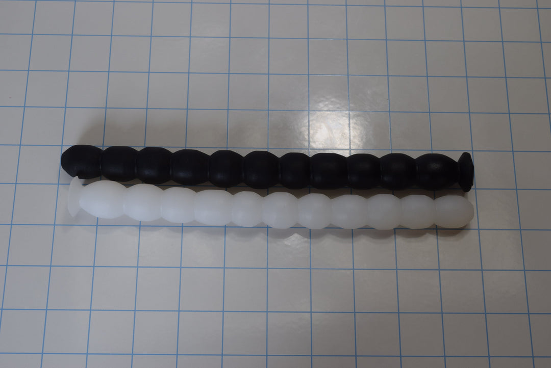 A silicone enema nozzle with small diameter balls or ribs along its length, displayed on a checkered background.