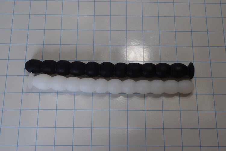 A silicone enema nozzle with small diameter balls or ribs along its length, displayed on a checkered background.