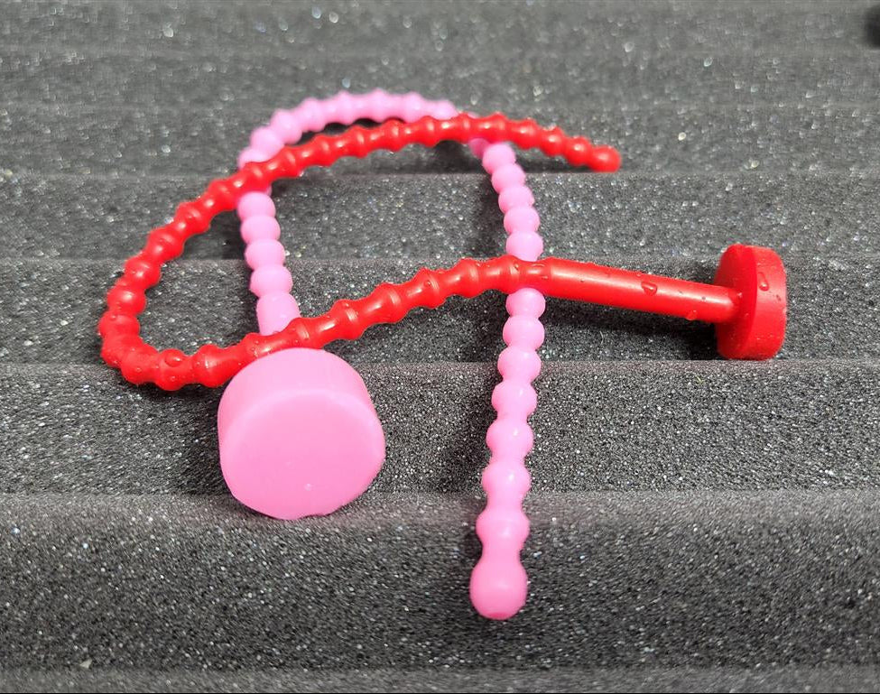 Alternative arrangement of soft, flexible SSND-RIB6 silicone urethral sounds in pink and red displaying 29 ribbed contours along the shaft, 6mm diameter, and flanged safety base.