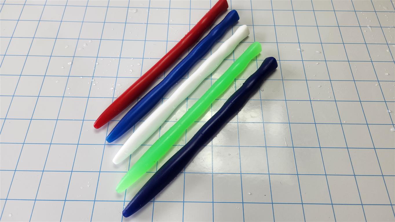 Five tri-sided ripple silicone sounds in red, royal blue, white, green, and dark blue arranged on a grid background.